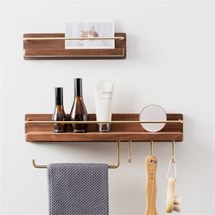 two wooden shelves holding personal care items on hooks next to towels and toothbrushes