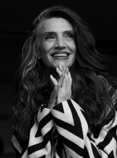 black and white photograph of woman smiling with her hands clasped in front of her face