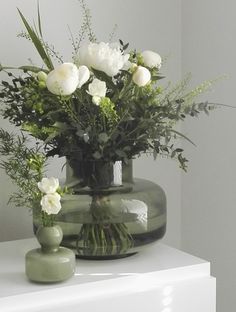 a vase with white flowers and greenery in it