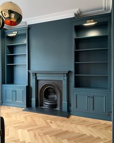 an empty living room with blue painted walls and wood flooring, built in bookshelves