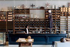 two people are standing at the counter in a room filled with shelves and other items