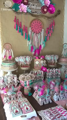 a table topped with lots of cakes and desserts covered in pink and turquoise decorations