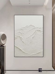 a large white painting hanging on the wall in a living room next to a vase