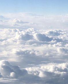 the view from an airplane looking down on clouds and blue sky with white fluffy clouds