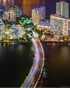 an aerial view of a city at night with the lights streaking across the water