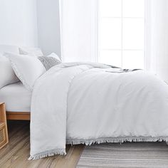 a bed with white sheets and pillows on top of it in a room next to a window