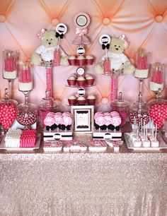 a table topped with lots of pink and white cupcakes