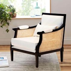 a wicker chair sitting on top of a rug next to a potted plant