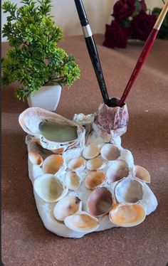 two chopsticks are sticking out of an oyster shell with shells on it and some plants in the background