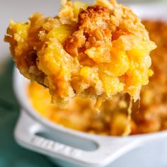 a spoon full of macaroni and cheese is being lifted from a casserole dish