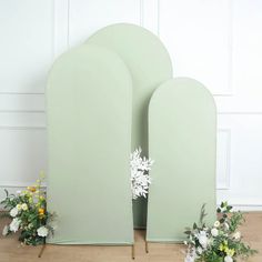 two green vases sitting next to each other on top of a wooden floor covered in flowers