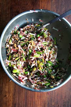 a bowl filled with food sitting on top of a wooden table next to a knife