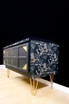 a black and gold sideboard with geometric designs on it's sides, against a dark background