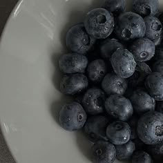 a white bowl filled with blueberries on top of a table