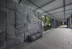 a stone wall with a bench in front of it on the side of a building