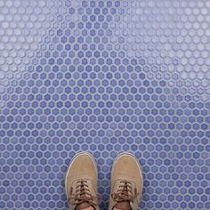 a pair of shoes sitting on top of a tiled floor next to a blue wall