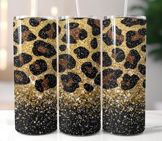 two black and gold leopard print tumblers with straws in them on a white background