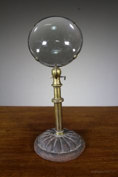 a glass ball on top of a metal stand with a wooden table in front of it