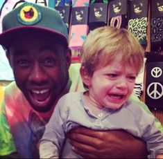 a man holding a little boy in his arms with peace signs on the wall behind him