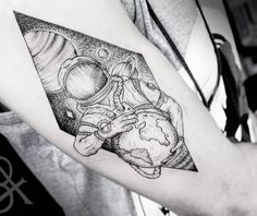 a black and white photo of a man's arm with an astronaut tattoo on it