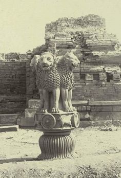 an old black and white photo of two lions on top of a pillar in front of a building