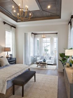 a bedroom with a large bed and chandelier hanging from it's ceiling