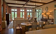 a living room filled with furniture next to a dining room table and two lamps hanging from the ceiling