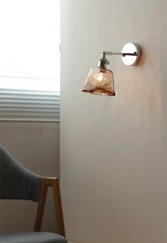 a light that is on the side of a wall next to a chair and window