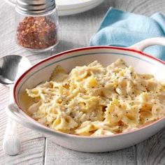 a bowl filled with macaroni and cheese on top of a table next to a spoon