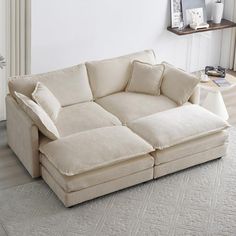 a large white couch sitting on top of a wooden floor next to a table and chair