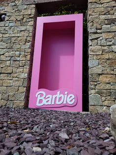 there is a pink box with the word barbie on it in front of a stone wall