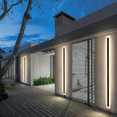 an exterior view of a modern house at night with lights on the side and shutters open