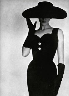 a black and white photo of a woman in a dress with a hat on her head