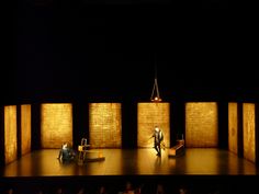 two men sitting on stage in front of an audience at a theater with lights behind them