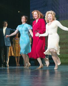 three women in dresses are dancing on stage