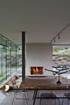 a living room with a fire place in the center and chairs around it on either side