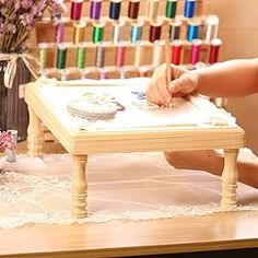 a woman is sitting at a sewing table with her hands on a piece of paper