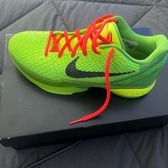 a pair of neon green and black shoes with red laces on top of a box