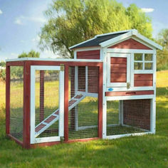 a red and white chicken coop in the grass