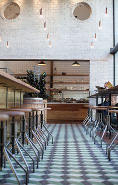 the interior of a restaurant with checkered flooring and white brick walls, along with bar stools