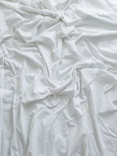 an unmade bed with white sheets and pillows