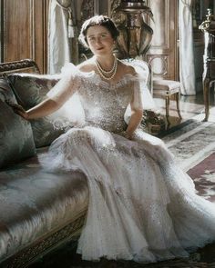 an old black and white photo of a woman in a gown sitting on a couch