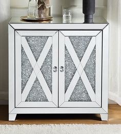 a white cabinet with two doors and some vases on top of the shelf next to it