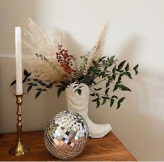 a vase with flowers and a disco ball on a wooden table next to a candle