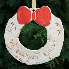 a ceramic ornament with a red bow hanging from a tree