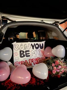 a car trunk with balloons, flowers and a sign that says can you be my girlfriend?