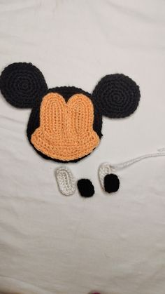 a crocheted mickey mouse hat and ear with two black ears on top of a white sheet