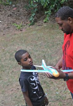 a man and boy are playing with a toy airplane