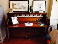 an old piano with two framed pictures on it