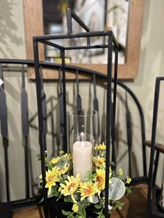 a candle sits in a vase with yellow flowers on the table next to some chairs